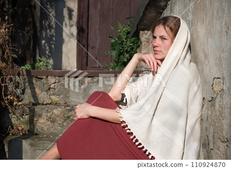 A woman in a headscarf is sitting on the old steps A woman in a headscarf is sitting on the old steps 110924870
