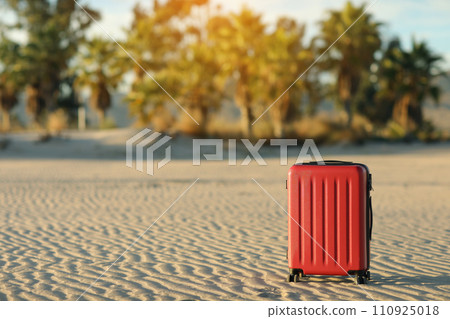 Red suitcase on the seashore sand beach on the palm trees backdrop. Vacation and tourism concept. Luggage for travel exotic abroad weekend getaway. Last minute trips, hot tours. Red suitcase on the seashore sand beach on the palm trees backdrop. Vacation and tourism concept. Luggage for travel exotic abroad weekend getaway. Last minute trips, hot tours. 110925018