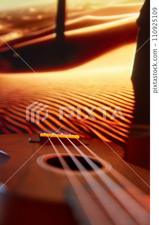 Close-up of acoustic guitar with desert dunes in the background. Cover visual for relaxation and meditation music tracks. 110925109