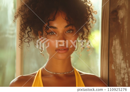 AI-generated content. Close-up portrait of a young African American woman wearing yellow sports top in a cozy home terrace. Attractive black girl with afro hairstyle and confident look. Outdoor 110925276