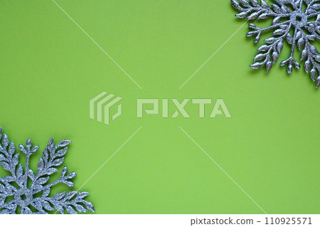 Christmas background with snowflakes. On a green background, two silver-blue snowflakes with sparkles are laid out. Happy New Year. Merry Christmas. Postcard or invitation. Copy space. Flat lay. 110925571