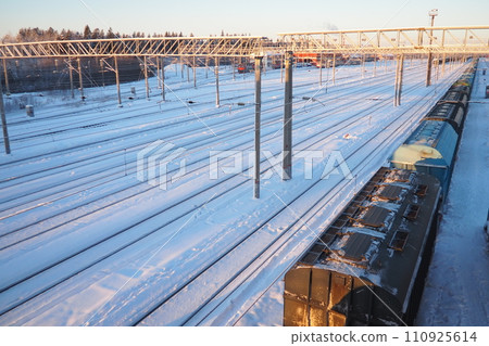 Railway station. Passenger freight trains on rails. Winter short polar day. Snow and snowdrifts 110925614