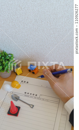 Man writing resume | Construction industry/application image Miniature helmet and truck 110926277