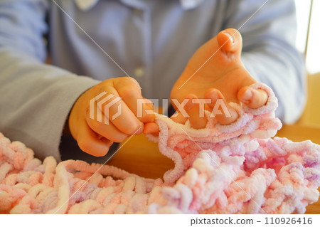 A 10-year-old 4th grade girl knits with her fingers. A 10-year-old 4th grade girl knits with her fingers. 110926416