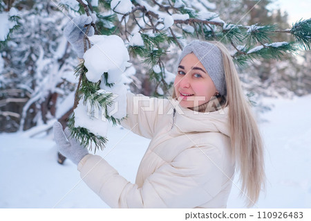 A woman in a white jacket and hat standing in the snow 110926483