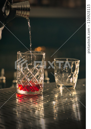 Cocktail pouring into a glass on a bar counter in a pub 110928115