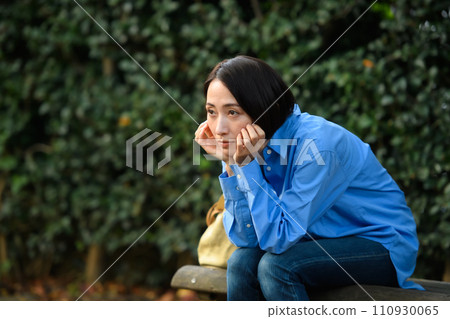 A worried woman sitting on a bench A worried woman sitting on a bench 110930065