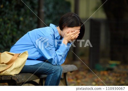 A worried woman sitting on a bench A worried woman sitting on a bench 110930067