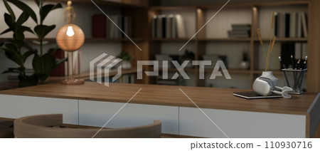 A copy space on a wooden desk and a large bookshelf in a modern home office at night. A copy space on a wooden desk and a large bookshelf in a modern home office at night. 110930716