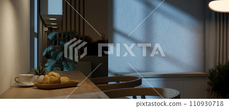 A side-view image of a dining table against the wall in a dining room at night with dim lighting. A side-view image of a dining table against the wall in a dining room at night with dim lighting. 110930718