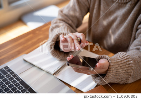 Cropped shot of a woman using her smartphone at a table at a cafe co-working space. 110930802