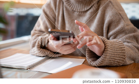 Cropped shot of a woman using her smartphone at a table at a cafe co-working space. 110930810