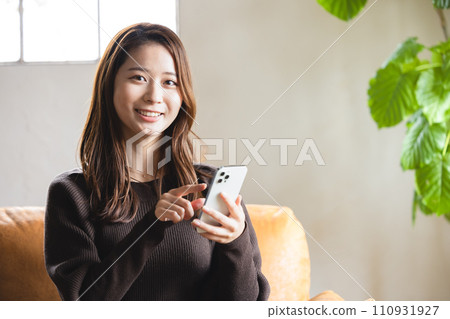 A woman who operates a smartphone in the room 110931927