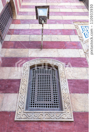 Mamluk architecture: rustic charm, weathered wooden window with star pattern, against aged brick wall Mamluk architecture: rustic charm, weathered wooden window with star pattern, against aged brick wall 110933930