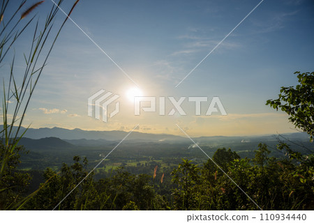 Dramatic sunset over mountain landscape. Beautiful landscape foggy hills twilight time. Blue golden sky sunrise dramatic beautiful landscape mountain. Dawn sky gold dusk time cloudscape with sunlight 110934440