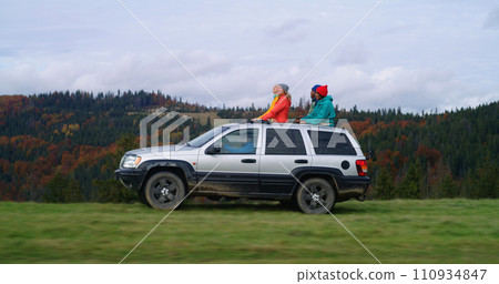 Hikers standing up through sunroof of car enjoy drive Hikers standing up through sunroof of car enjoy drive 110934847