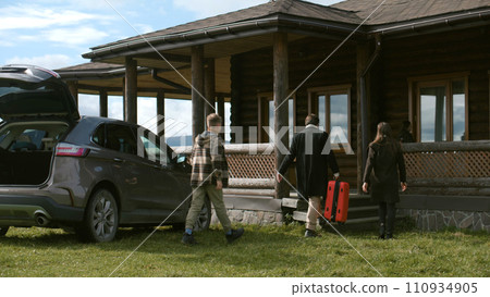 Happy family gets out of the car, settles into rented cottage or moves to new home Happy family gets out of the car, settles into rented cottage or moves to new home 110934905