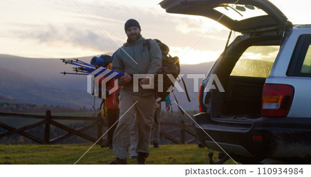 Tourist family or friends puts their backpacks into the trunk of car after hike 110934984