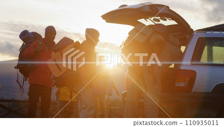 Hikers packs backpacks into trunk of car preparing for hike in mountains Hikers packs backpacks into trunk of car preparing for hike in mountains 110935011