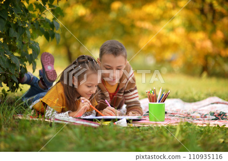 Girl and boy drawing in autumn park 110935116
