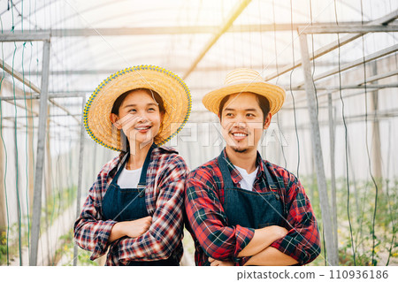 Happy Asian couple farmers working in tomato hydroponic farm. Smiling man and woman crossed arms with vegetable success. Portrait of confident husband and wife in greenhouse. Quality farming. 110936186