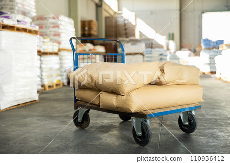 Bags are stacked on top of each other and lie in stacks in warehouse of building materials store. 110936412