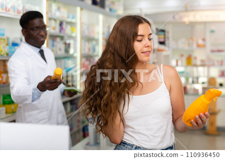 Young woman who came to the pharmacy chooses a hair care remedy 110936450