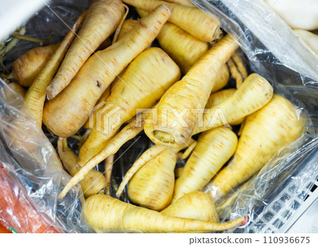Organic vegetables - fresh raw parsnips in a box on vegetable market showcase Organic vegetables - fresh raw parsnips in a box on vegetable market showcase 110936675