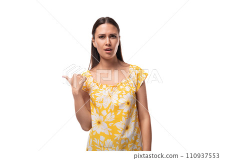 Caucasian young woman with straight black hair dressed in a yellow sundress points with her hand to 110937553