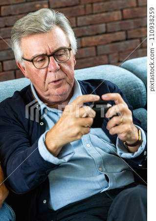 Senior Man Concentrated on Smartphone Gaming Senior Man Concentrated on Smartphone Gaming 110938259