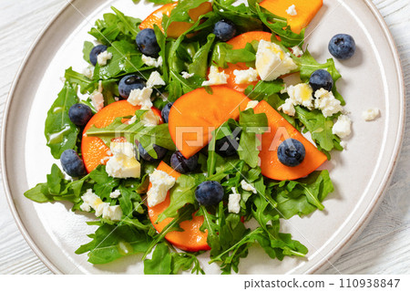 arugula persimmon cheese berries salad, top view arugula persimmon cheese berries salad, top view 110938847