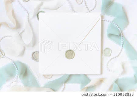 Envelope near light green and beige decorations and silk ribbons on white table top view, mockup Envelope near light green and beige decorations and silk ribbons on white table top view, mockup 110938883