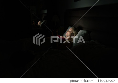 woman in bed before going to sleep with phone in hand 110938902