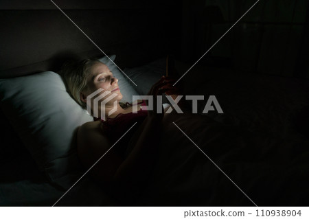 woman in bed before going to sleep with phone in hand 110938904