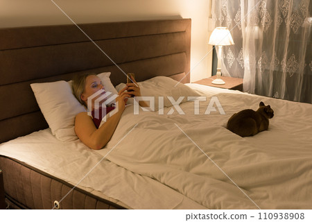 woman in bed before going to sleep with phone in hand 110938908