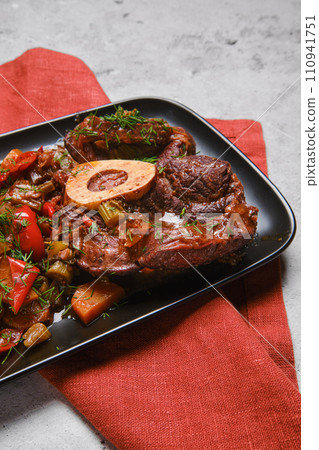 Closeup view of beef ossobuco and chopped vegetables in plate 110941751