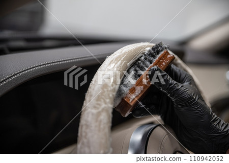 Car wash employee or a car detailing studio thoroughly cleans a light leather steering wheel Car wash employee or a car detailing studio thoroughly cleans a light leather steering wheel 110942052