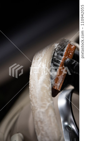 Car wash employee or a car detailing studio thoroughly cleans a light leather steering wheel Car wash employee or a car detailing studio thoroughly cleans a light leather steering wheel 110942055