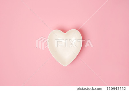 A white heart-shaped plate on pink background. The concept of love and happiness on Valentine's Day 110943532