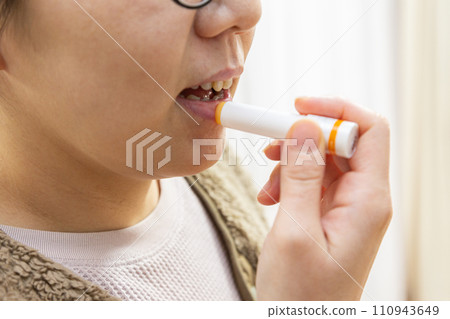 Woman applying lip balm to her lips Woman applying lip balm to her lips 110943649