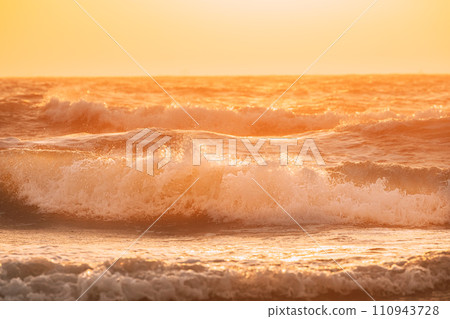 Sea water surface at sunset. Natural sunrise warm colors of ocean. Sea ocean water surface with foaming small waves at sunset. Evening sunlight sunshine above sea. Amazing landscape scenery. Nature 110943728