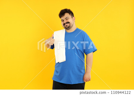 A fat man is tired after training, on a yellow background. 110944122