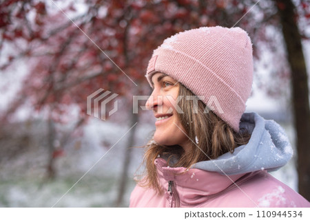 Winter Elegance: Portrait of a Beautiful Girl in a Snowy European Village. Winter lifestyle portrait of cheerful pretty girl. Smiling and having fun in the snow park. Snowflakes falling down 110944534