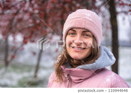 Winter Elegance: Portrait of a Beautiful Girl in a Snowy European Village. Winter lifestyle portrait of cheerful pretty girl. Smiling and having fun in the snow park. Snowflakes falling down 110944646
