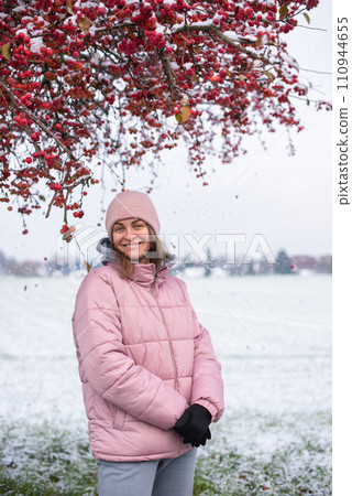 Winter Elegance: Portrait of a Beautiful Girl in a Snowy European Village. Winter lifestyle portrait of cheerful pretty girl. Smiling and having fun in the snow park. Snowflakes falling down Winter Elegance: Portrait of a Beautiful Girl in a Snowy European Village. Winter lifestyle portrait of cheerful pretty girl. Smiling and having fun in the snow park. Snowflakes falling down 110944655
