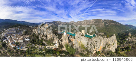 Landmarks of Spain. medieval village Guadalest, aerial drone view scenery with castle on the rocks and turquoise lake. Alicante province Landmarks of Spain. medieval village Guadalest, aerial drone view scenery with castle on the rocks and turquoise lake. Alicante province 110945003