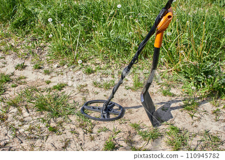 Magnetic metal detector and shovel for searching for precious metals and coins against the background of a path in a field Magnetic metal detector and shovel for searching for precious metals and coins against the background of a path in a field 110945782