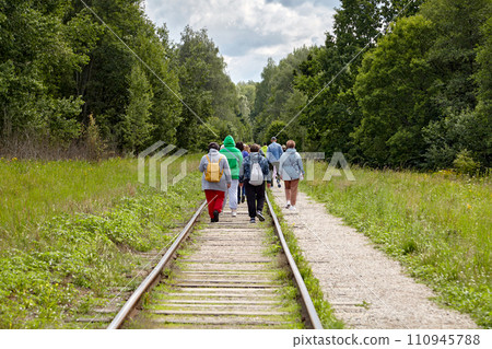 A group of migrant refugees moves along abandoned railway tracks in the forest 110945788