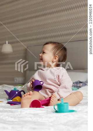 happy cute little child girl playing and pretending drinking tea from toy cups on bed happy cute little child girl playing and pretending drinking tea from toy cups on bed 110946034