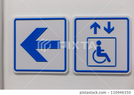 A blue arrow and elevator access signs disabled person on the wall A blue arrow and elevator access signs disabled person on the wall 110946350